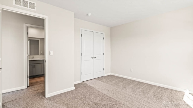 unfurnished bedroom featuring carpet flooring, sink, and a closet