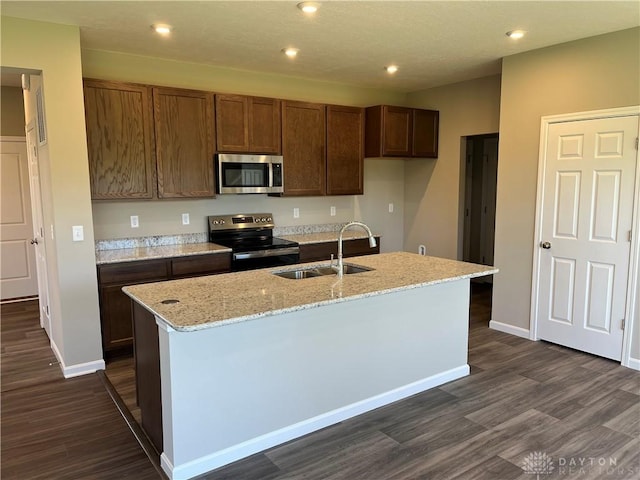 kitchen with dark hardwood / wood-style floors, sink, stainless steel appliances, and an island with sink