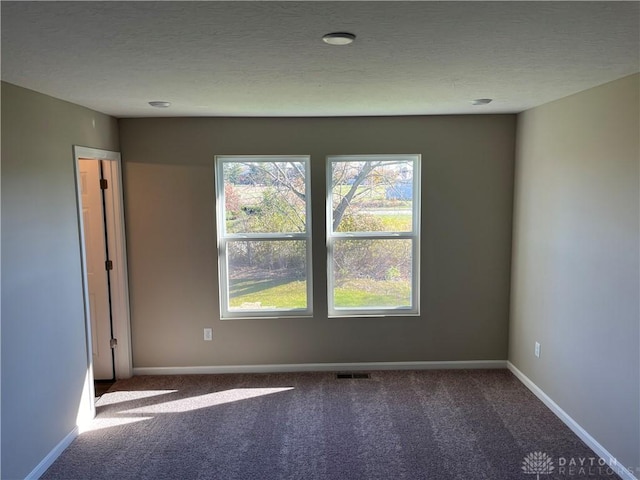 carpeted spare room featuring a textured ceiling