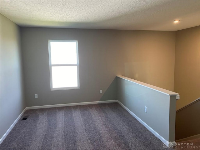 spare room featuring carpet flooring and a textured ceiling