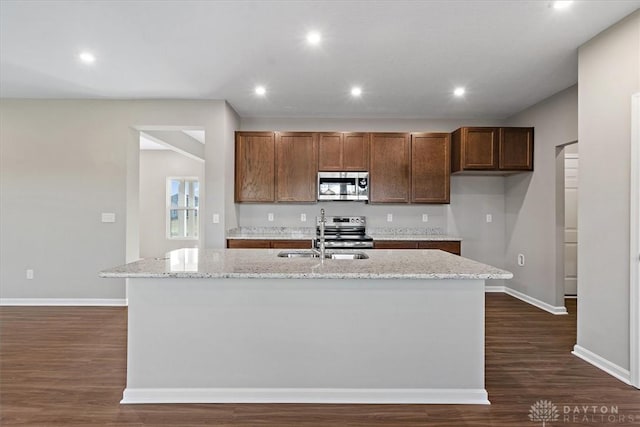 kitchen featuring stainless steel appliances, sink, dark hardwood / wood-style flooring, and an island with sink