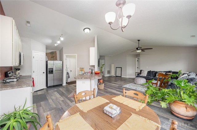 dining space featuring sink, ceiling fan with notable chandelier, dark hardwood / wood-style flooring, track lighting, and vaulted ceiling