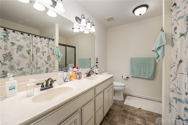 bathroom with toilet, double sink vanity, and tile patterned floors