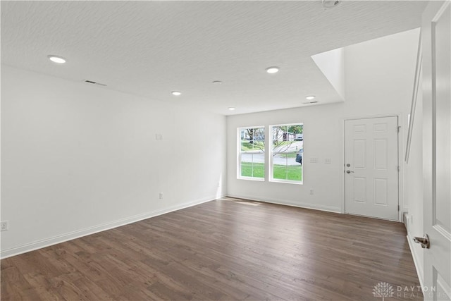 empty room featuring a textured ceiling and dark hardwood / wood-style flooring