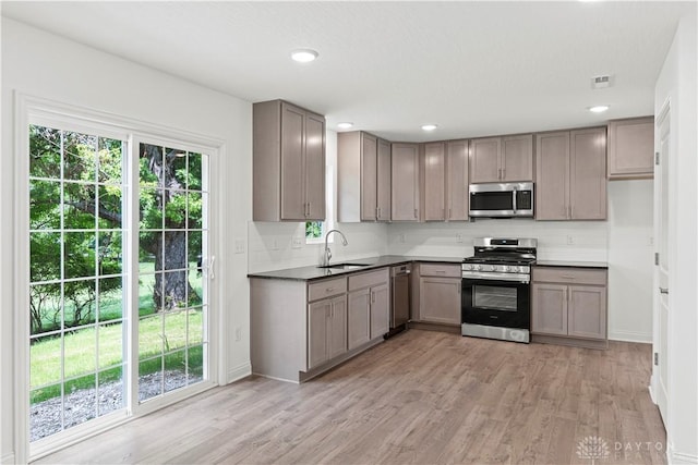 kitchen featuring gray cabinets, decorative backsplash, sink, light wood-type flooring, and stainless steel appliances