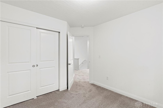 unfurnished bedroom with light colored carpet and a closet