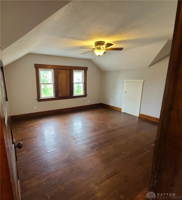 additional living space featuring ceiling fan, vaulted ceiling, dark hardwood / wood-style floors, and a textured ceiling