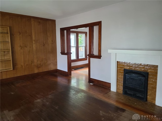 unfurnished living room with dark wood-type flooring and wood walls