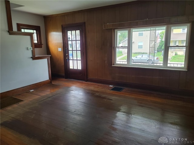 entrance foyer with plenty of natural light, dark hardwood / wood-style flooring, and wood walls