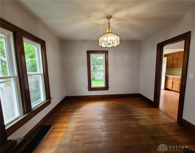 empty room featuring dark hardwood / wood-style floors and a chandelier