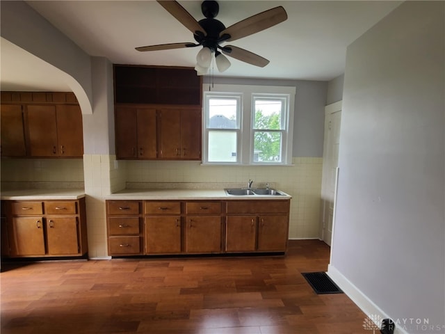 kitchen featuring hardwood / wood-style flooring, ceiling fan, sink, and tile walls