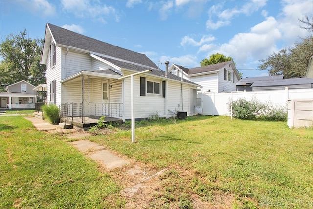 back of property with central AC and a lawn