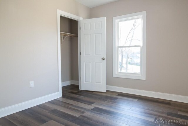 unfurnished bedroom with dark wood-type flooring, a closet, and multiple windows