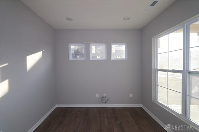 spare room with a healthy amount of sunlight and dark hardwood / wood-style flooring