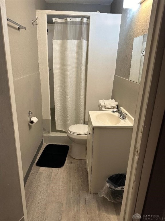 bathroom featuring vanity, toilet, curtained shower, and hardwood / wood-style flooring