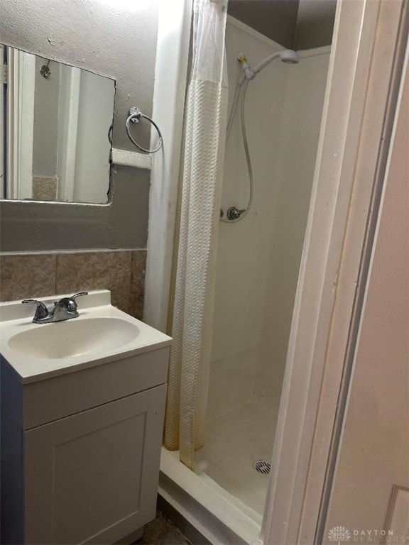 bathroom featuring a shower with shower curtain, decorative backsplash, and vanity