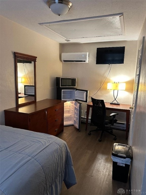 bedroom with a textured ceiling, baseboard heating, an AC wall unit, and hardwood / wood-style flooring