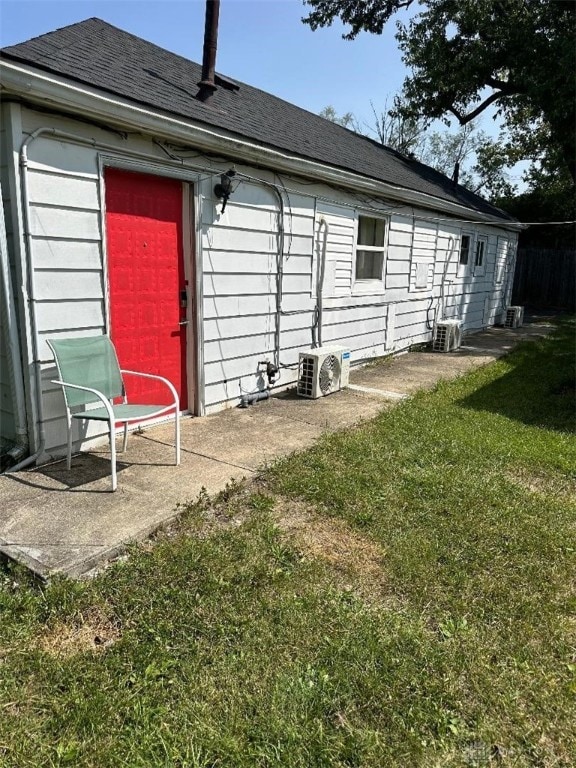 rear view of property featuring a lawn and central AC unit