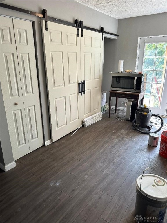 interior space featuring a textured ceiling, a barn door, and dark hardwood / wood-style floors