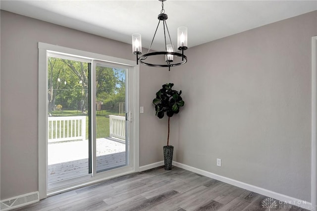 unfurnished dining area featuring light hardwood / wood-style floors and a notable chandelier