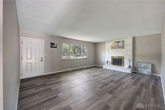 unfurnished living room featuring dark hardwood / wood-style floors and a stone fireplace