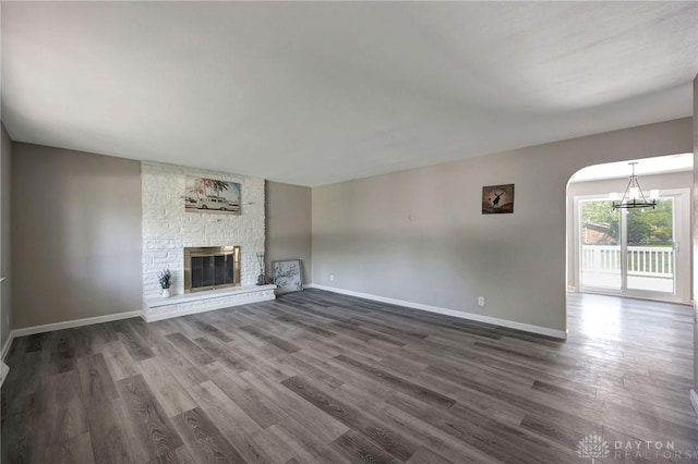 unfurnished living room with a large fireplace, dark hardwood / wood-style floors, and a notable chandelier