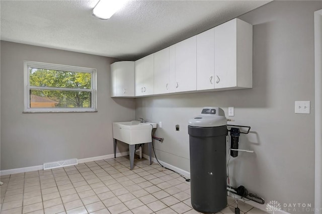 washroom with cabinets, light tile patterned flooring, electric dryer hookup, and a textured ceiling