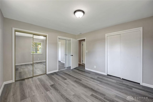 unfurnished bedroom with multiple closets and wood-type flooring