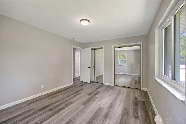 unfurnished bedroom with multiple closets and light wood-type flooring