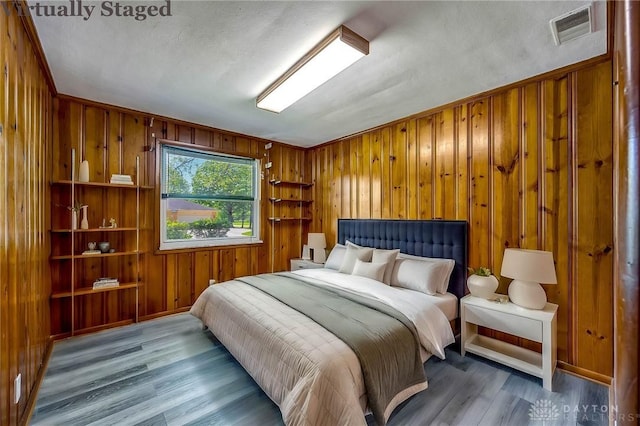 bedroom with wood-type flooring and wood walls