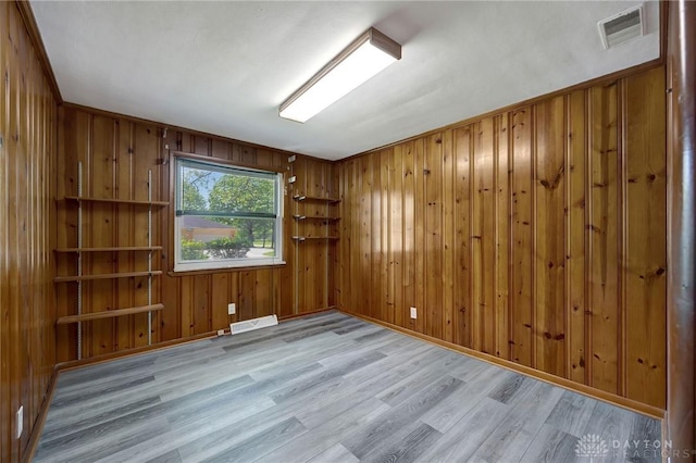 spare room featuring wooden walls and light hardwood / wood-style flooring