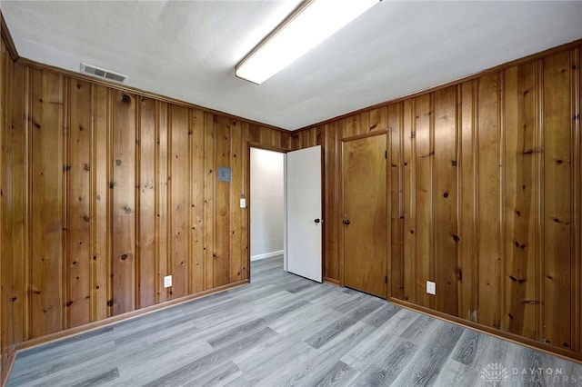 spare room with wooden walls and light hardwood / wood-style flooring