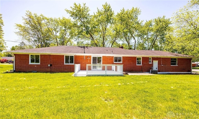 rear view of house with a wooden deck, a yard, and central AC