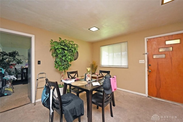 dining room featuring light colored carpet and baseboards