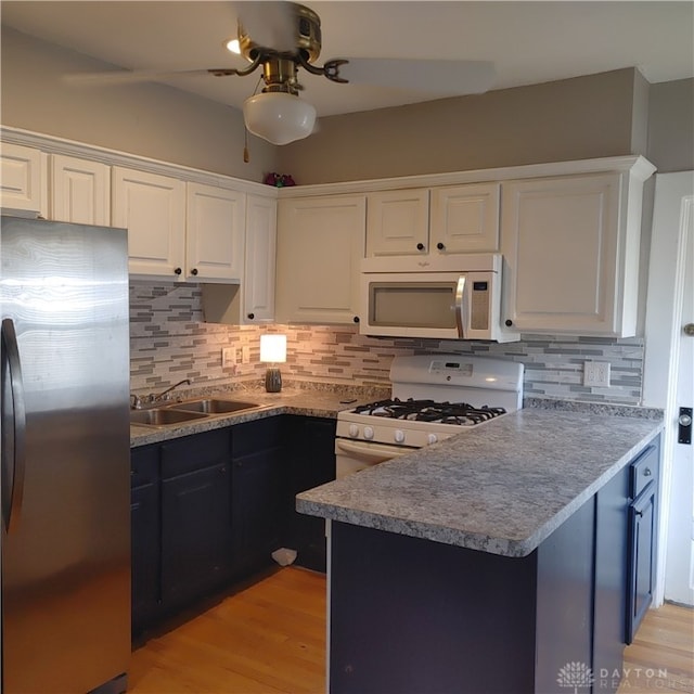 kitchen featuring light wood-type flooring, backsplash, white appliances, and white cabinetry