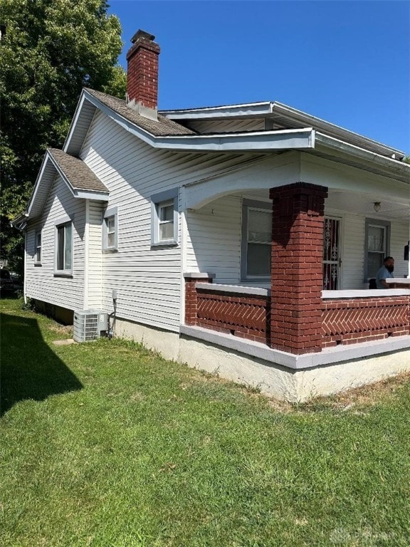 back of house with central AC and a lawn