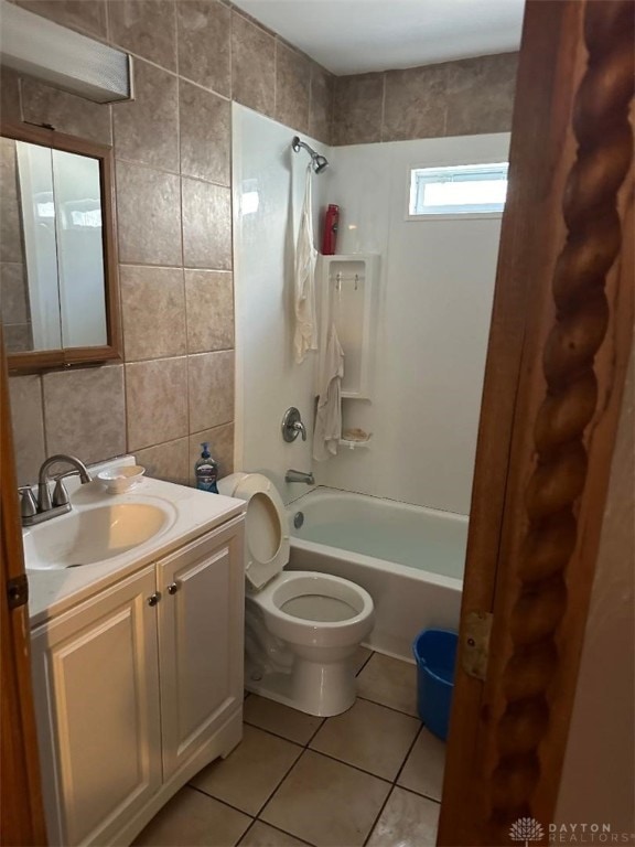 full bathroom with tile walls, tiled shower / bath combo, tile patterned flooring, vanity, and toilet