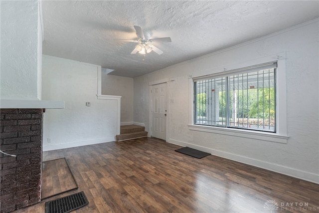 unfurnished living room with a textured ceiling, dark wood-type flooring, ceiling fan, and ornamental molding