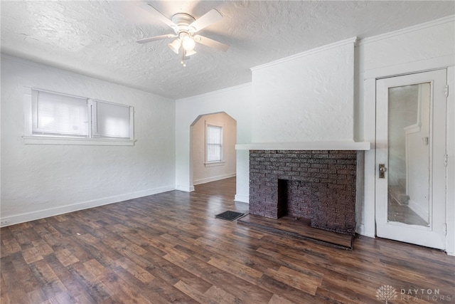 unfurnished living room featuring dark wood-type flooring, ceiling fan, plenty of natural light, and a textured ceiling