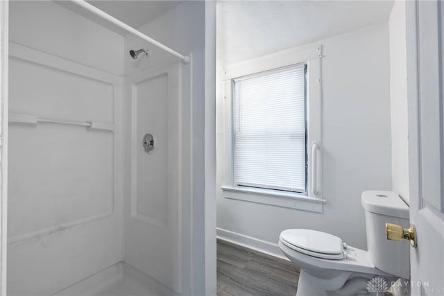 bathroom featuring a shower, toilet, and wood-type flooring