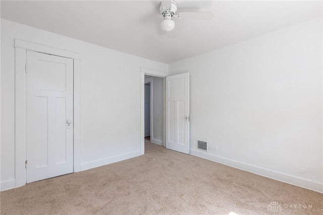 empty room with ceiling fan and light carpet