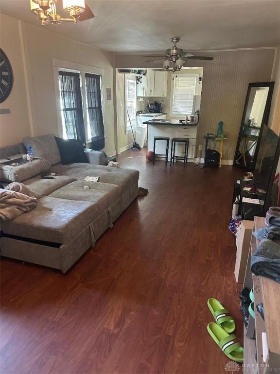 living room featuring ceiling fan with notable chandelier and dark hardwood / wood-style flooring