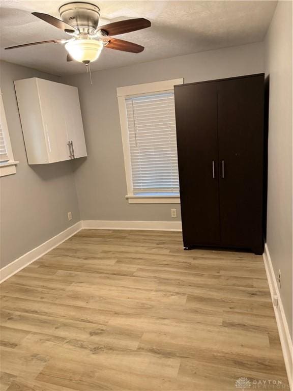 unfurnished bedroom with light wood finished floors, a ceiling fan, and baseboards