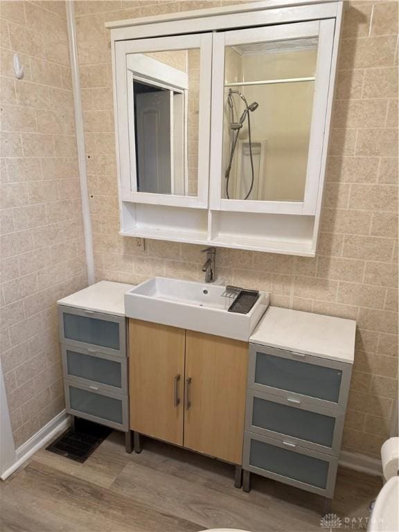 bathroom featuring vanity, tile walls, wood finished floors, and visible vents