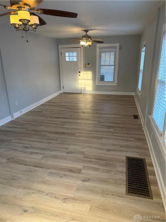 unfurnished room featuring wood finished floors, a ceiling fan, visible vents, and baseboards