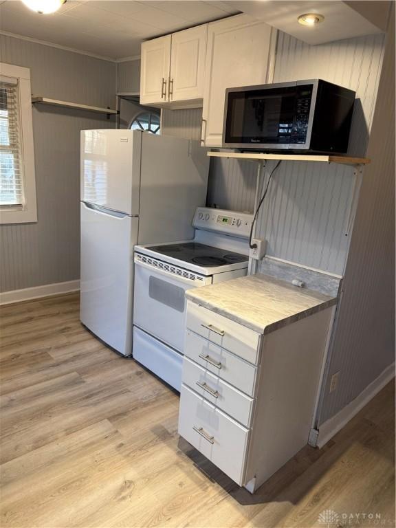 kitchen featuring white electric stove, ornamental molding, light countertops, white cabinets, and light wood-style floors