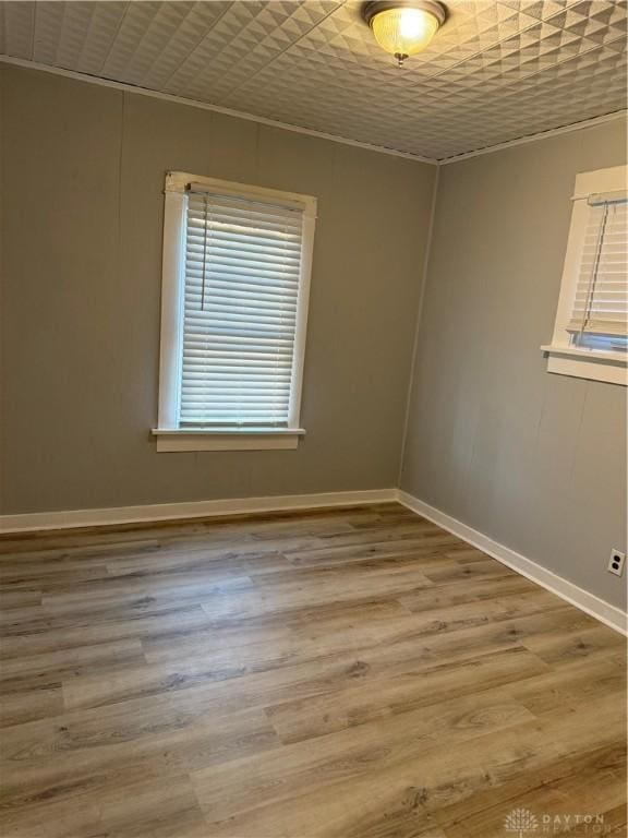 spare room featuring an ornate ceiling, baseboards, and wood finished floors