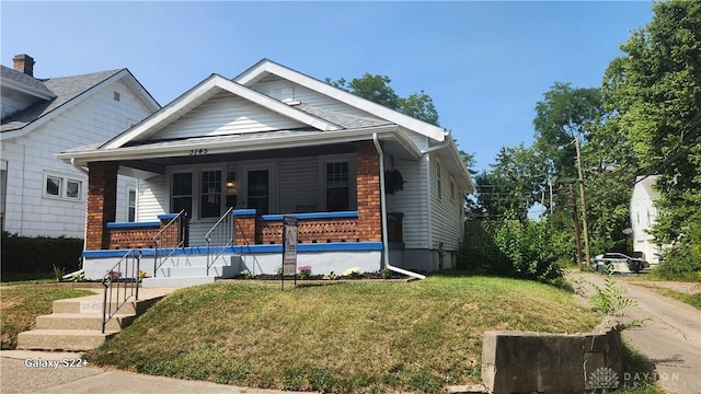 bungalow-style house featuring a porch and a front lawn