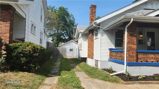 view of side of home with fence and a chimney