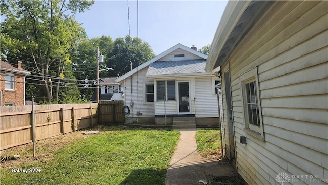 exterior space with entry steps, a yard, roof with shingles, and fence